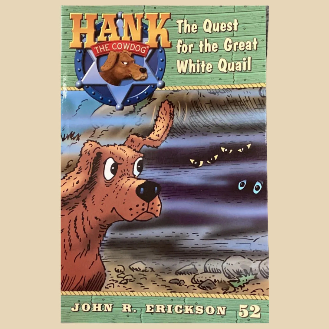 Children's book titled 'Hank the Cowdog: The Quest for the Great White Quail' on a shelf.