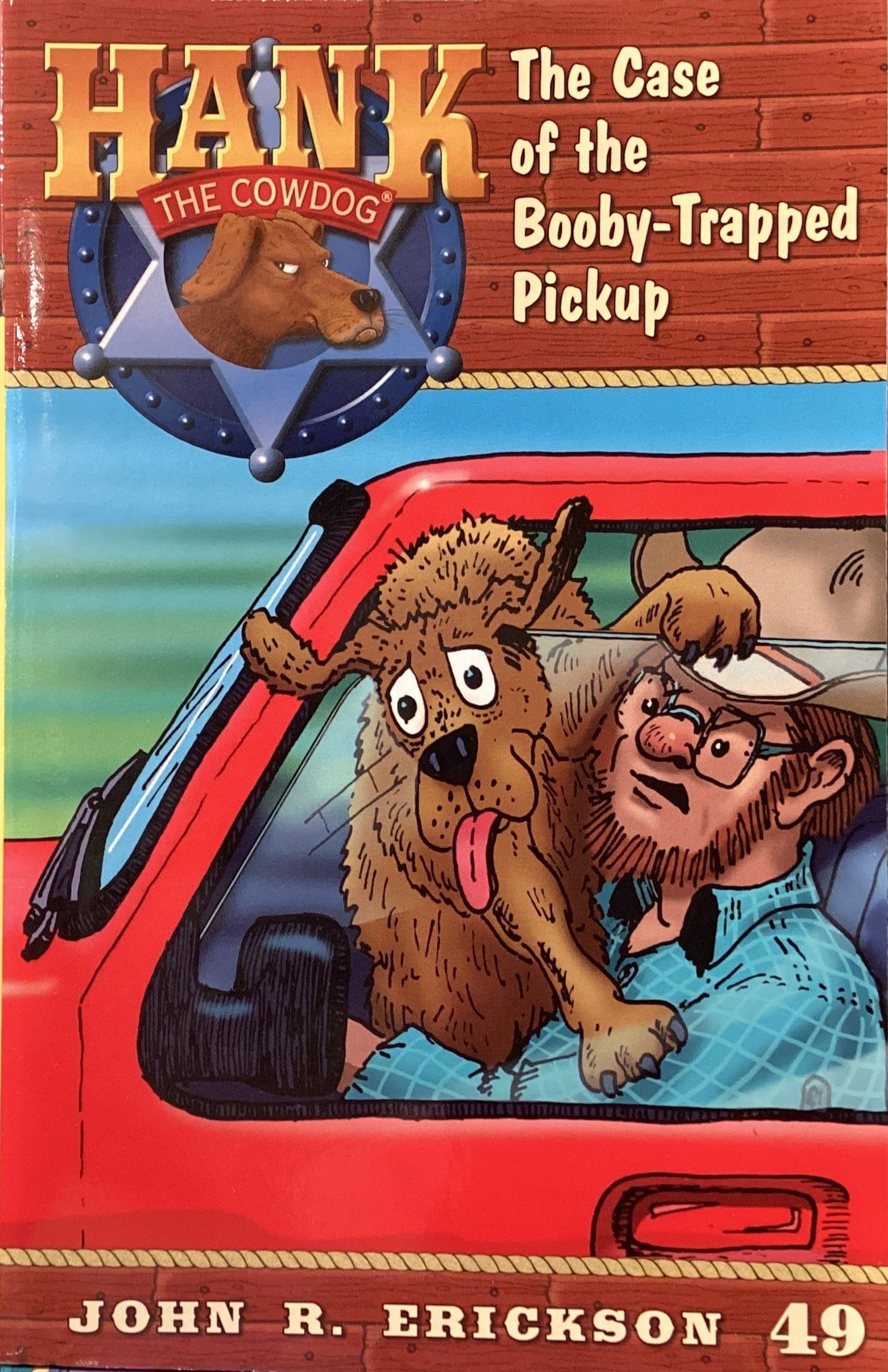 Book titled 'Hank the Cowdog: The Case of the Bobby-Trapped Pickup' by John R. Erickson on a gray surface.
