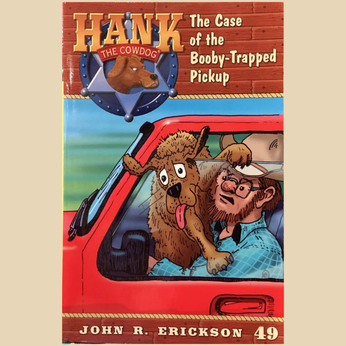 Book titled 'Hank the Cowdog: The Case of the Bobby-Trapped Pickup' by John R. Erickson on a gray surface.