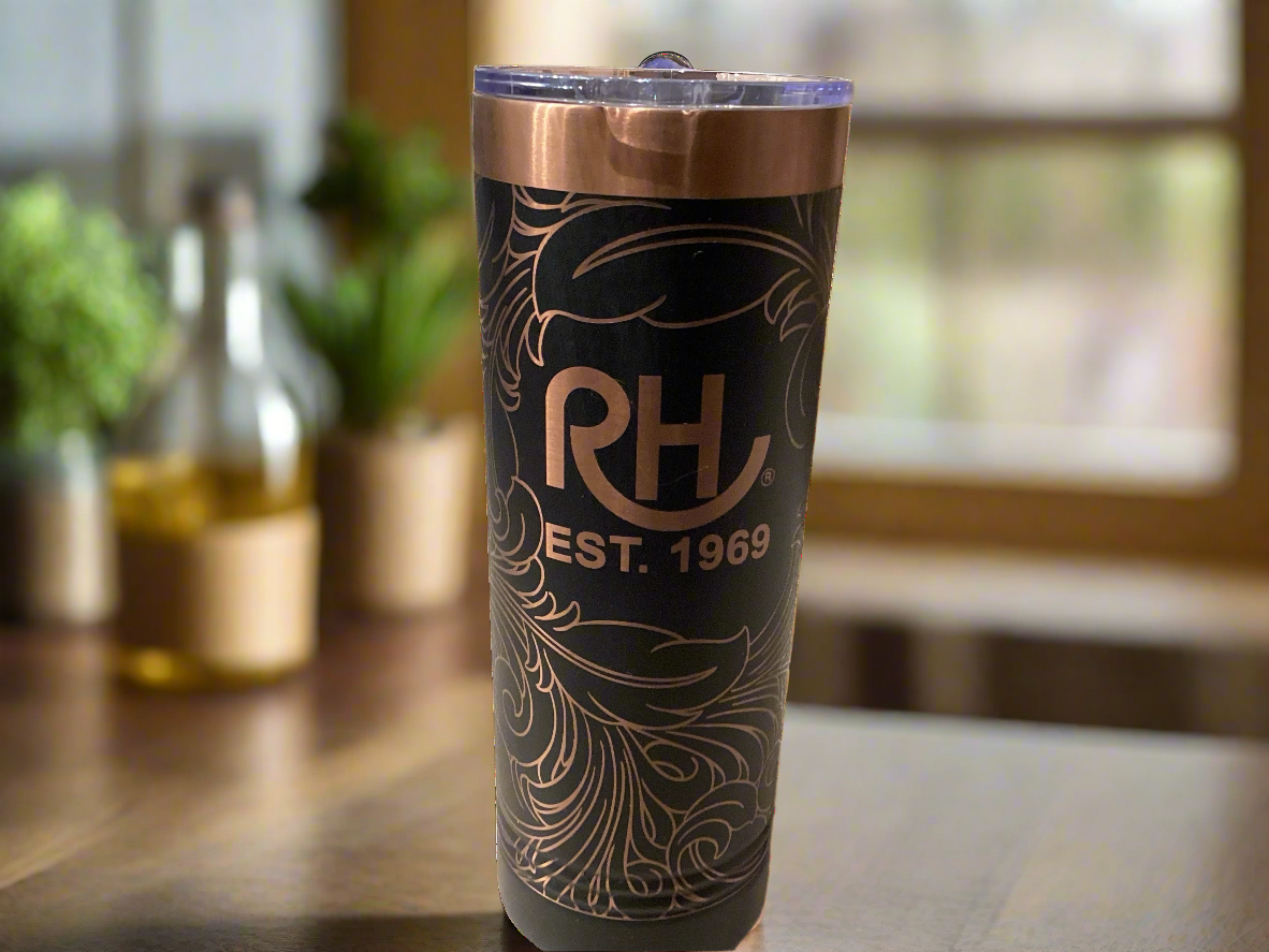 A black metal tumbler with tooled leather pattern and metallic bronze edges, with the initials 'RH' and the year '1989' engraved on it.