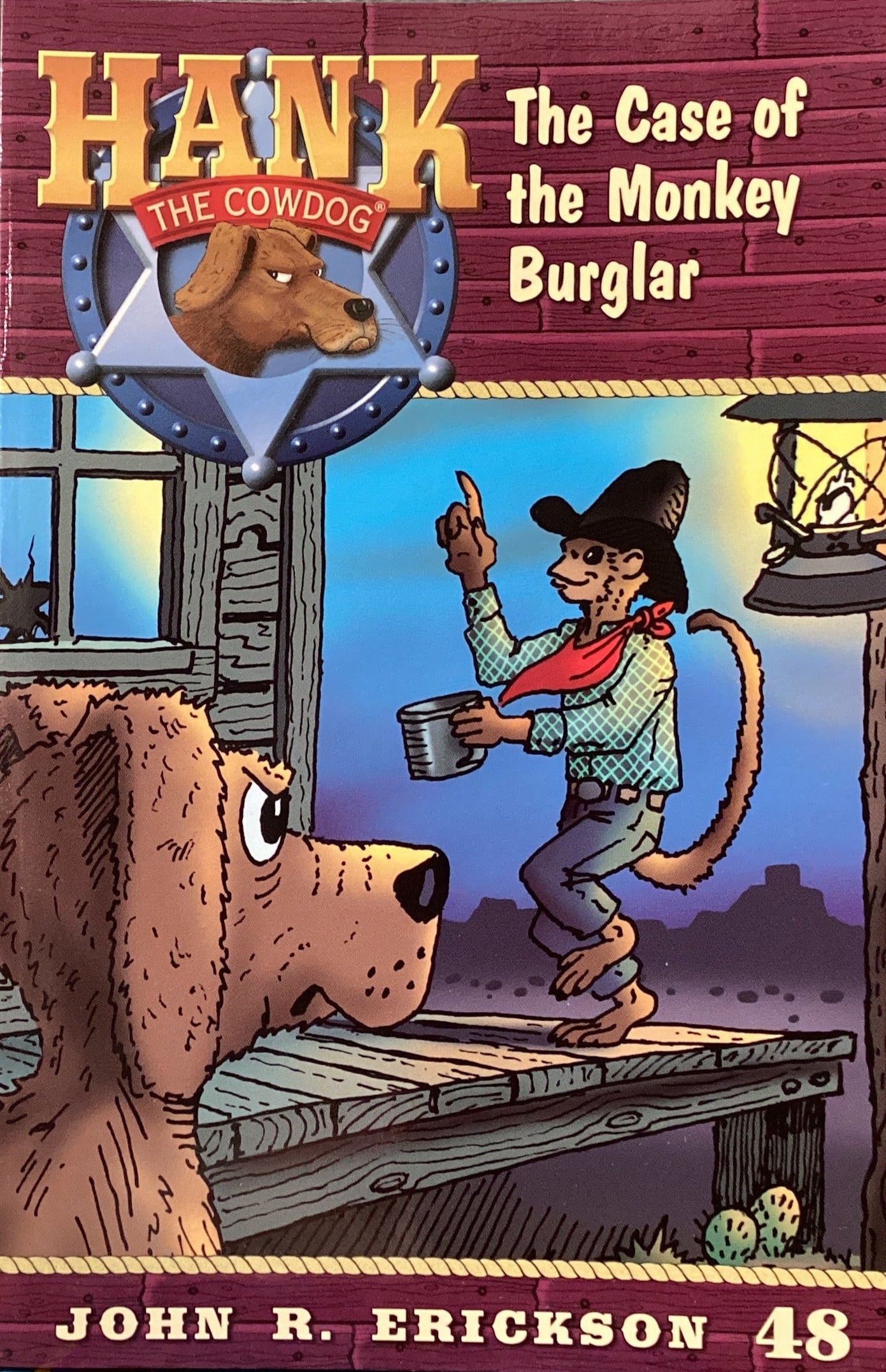 Book titled 'Hank the Cowdog: The Case of the Monkey Burglar' by John R. Erickson on a gray wall.
