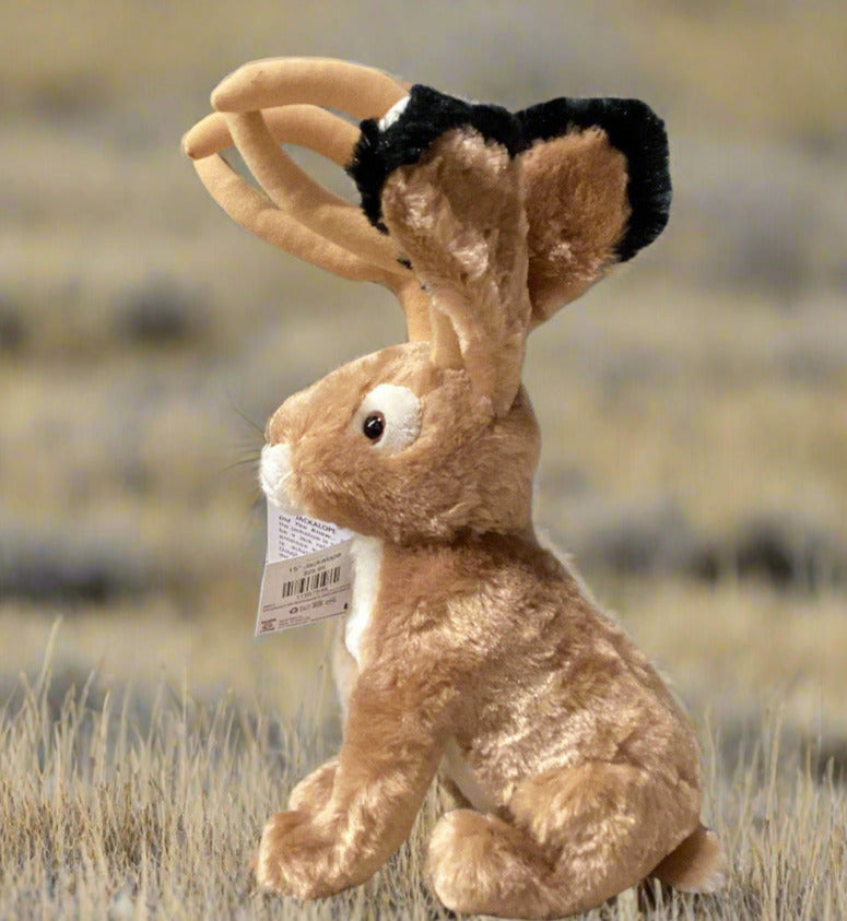 Plush rabbit toy on a shelf with a gray wall background