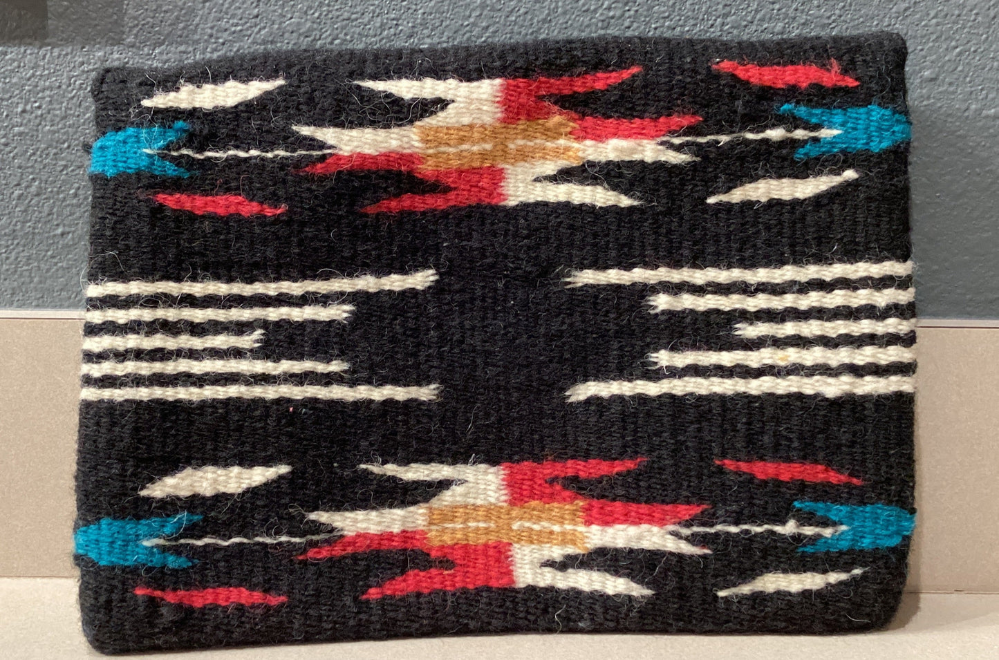 Woven pouch with geometric pattern on a gray surface