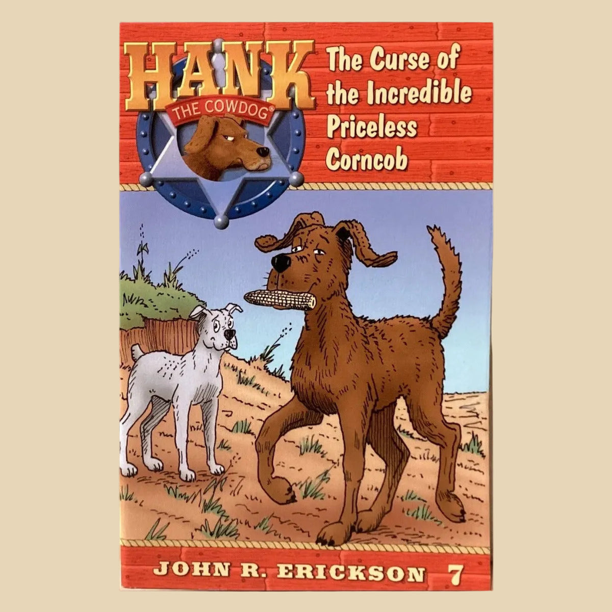 Book cover of 'Hank the Cowdog' with a cartoon dog and goat on a red background