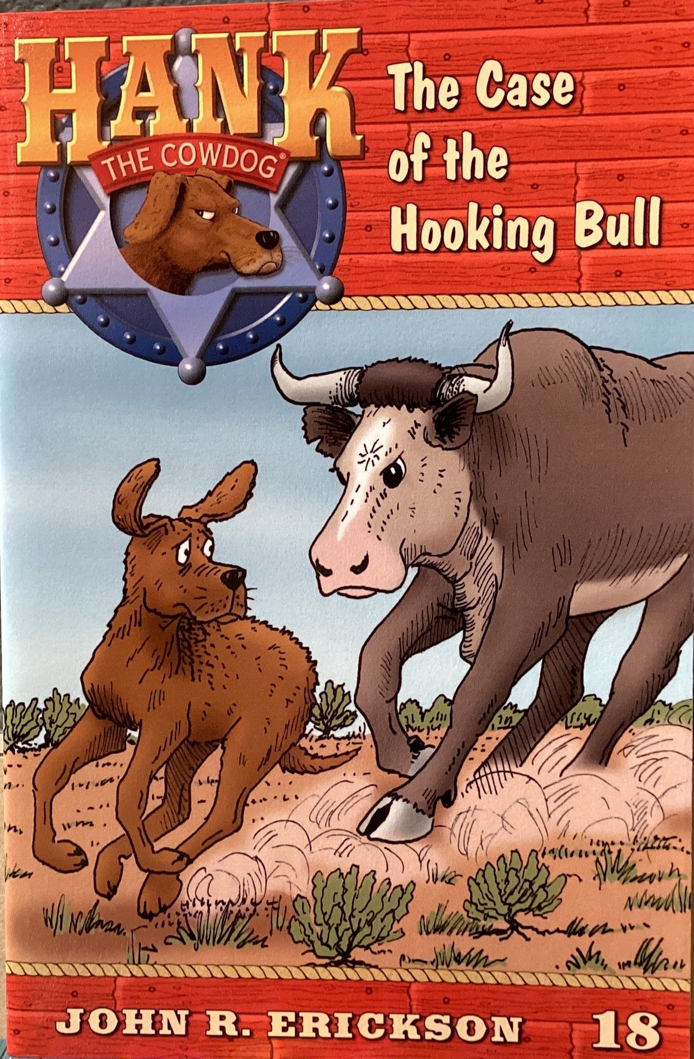 Book cover of 'Hank the Cowdog: The Case of the Hooking Bull' by John R. Erickson on a gray surface.