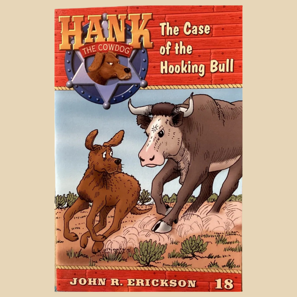 Book cover of 'Hank the Cowdog: The Case of the Hooking Bull' by John R. Erickson on a gray surface.