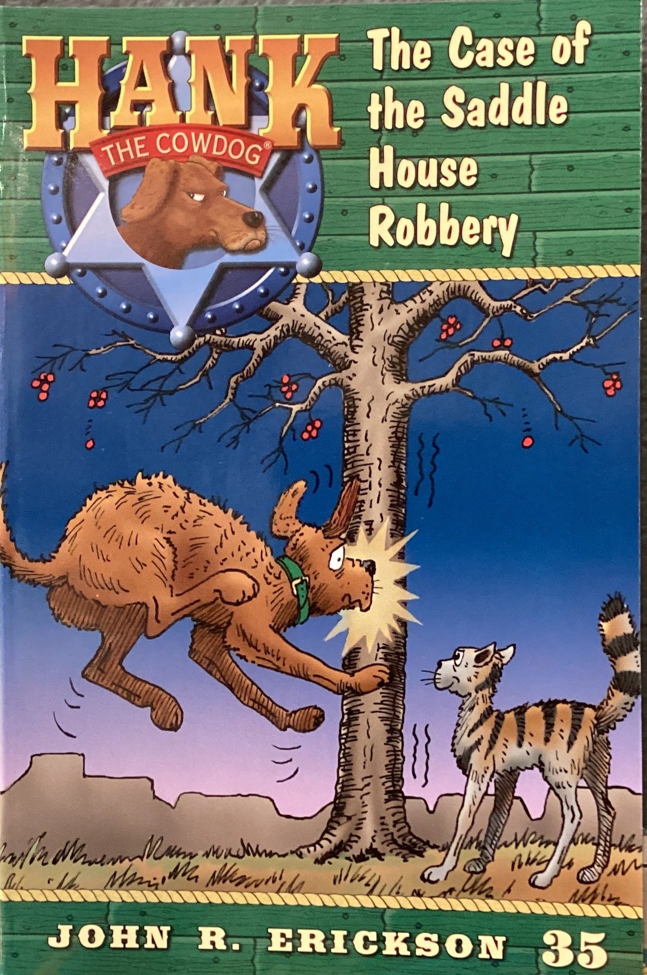 Book cover of 'Hank the Cowdog: The Case of the Saddle House Robbery' by John R. Erickson on a gray surface.
