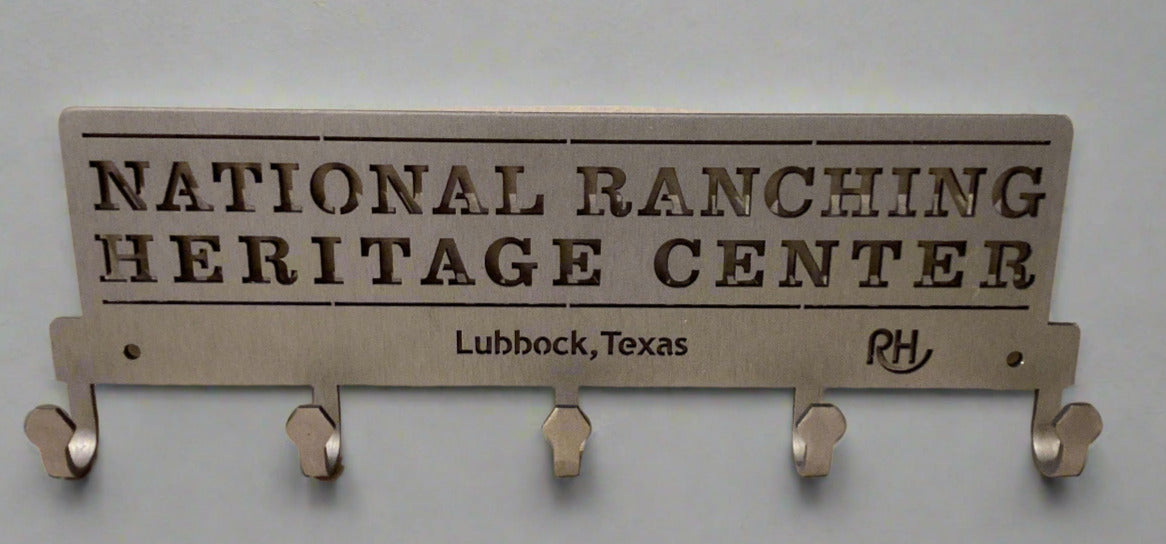 Metal key holder with 'National Ranching Heritage Center' text on a beige surface.