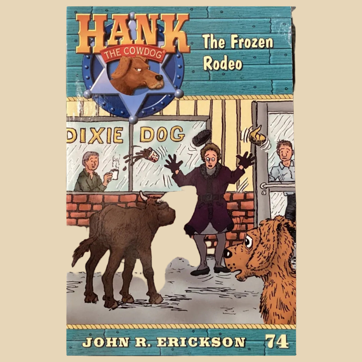 Book titled 'Hank the Cowdog: The Frozen Rodeo' by John R. Erickson on a surface with a dark gray wall background.