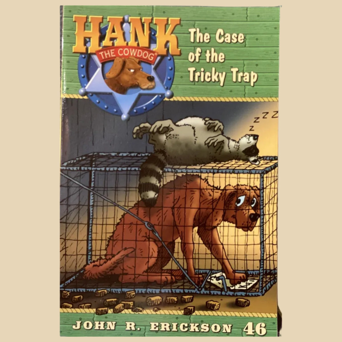 Book cover of 'Hank the Cowdog: The Case of the Tricky Trap' by John R. Erickson on a gray wall.