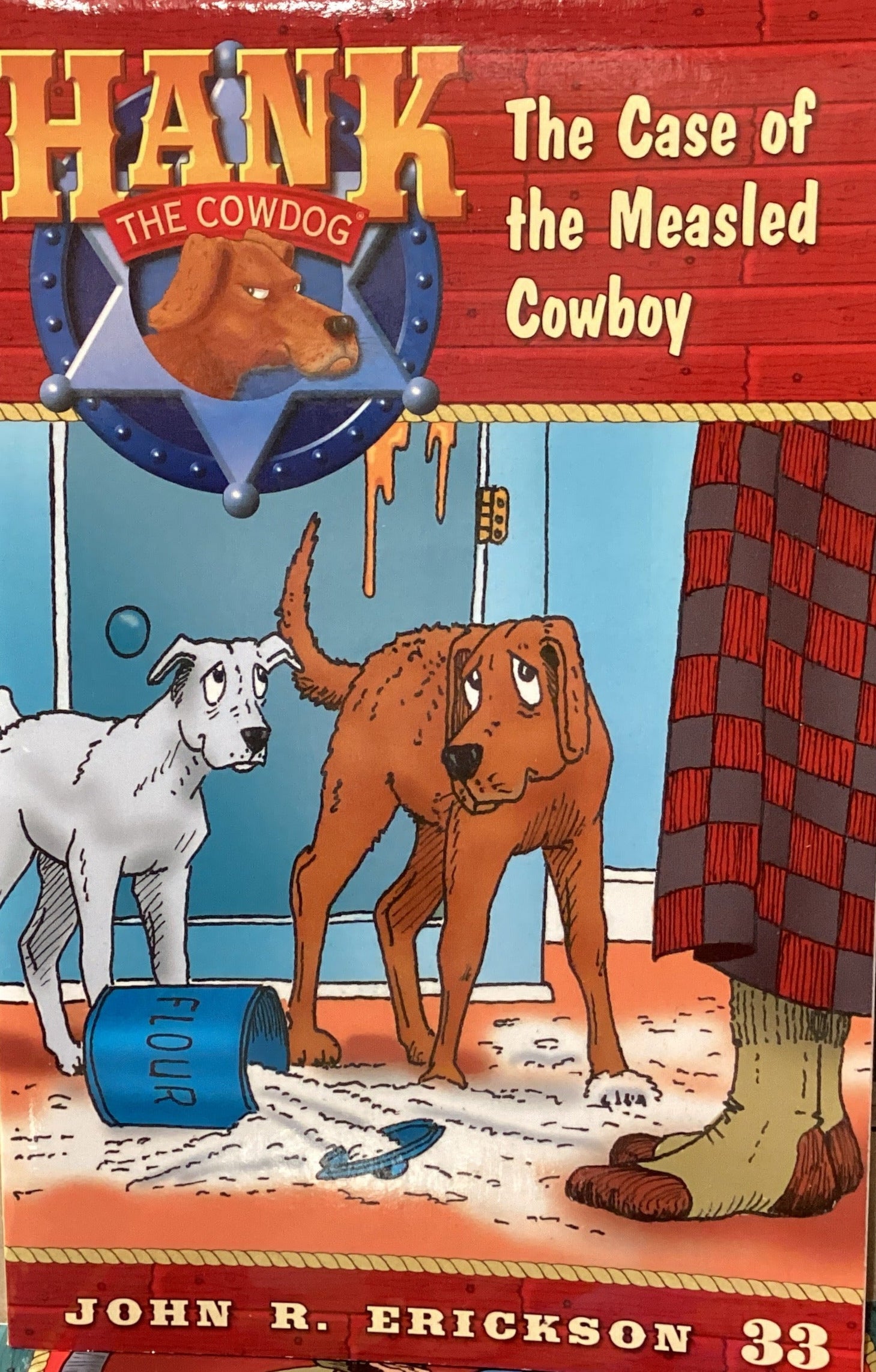 Book titled 'Hank the Cowdog: The Case of the Measled Cowboy' by John R. Erickson on a gray surface.