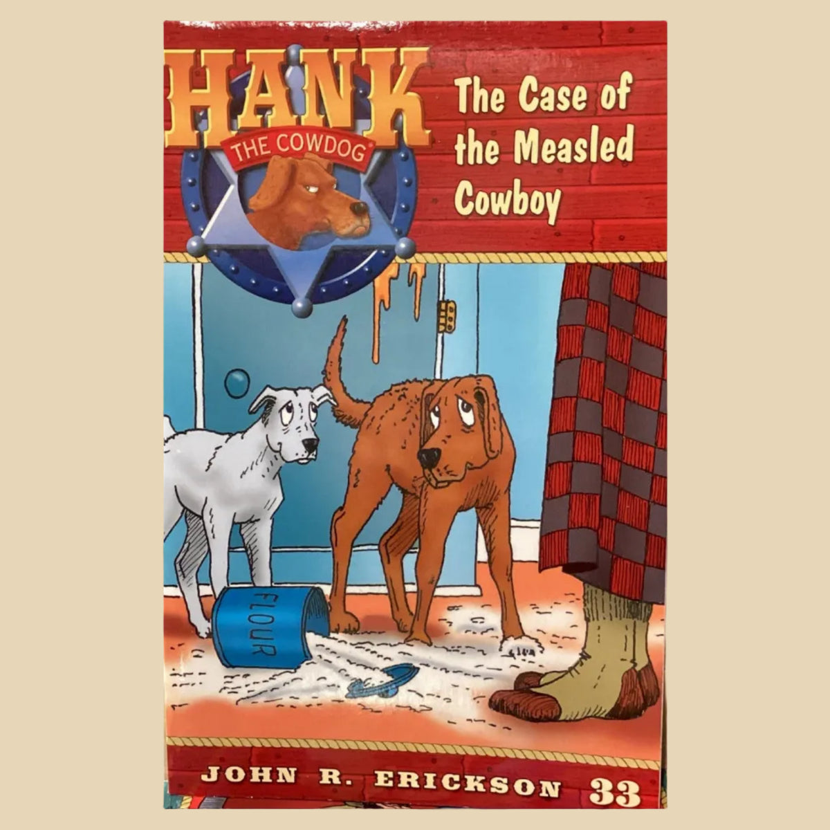 Book titled 'Hank the Cowdog: The Case of the Measled Cowboy' by John R. Erickson on a gray surface.