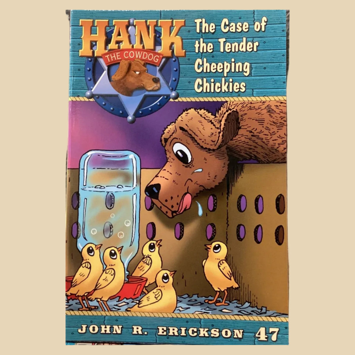 Book cover of 'Hank the Cowdog: The Case of the Tender Cheeping Chickies' by John R. Erickson on a gray wall.