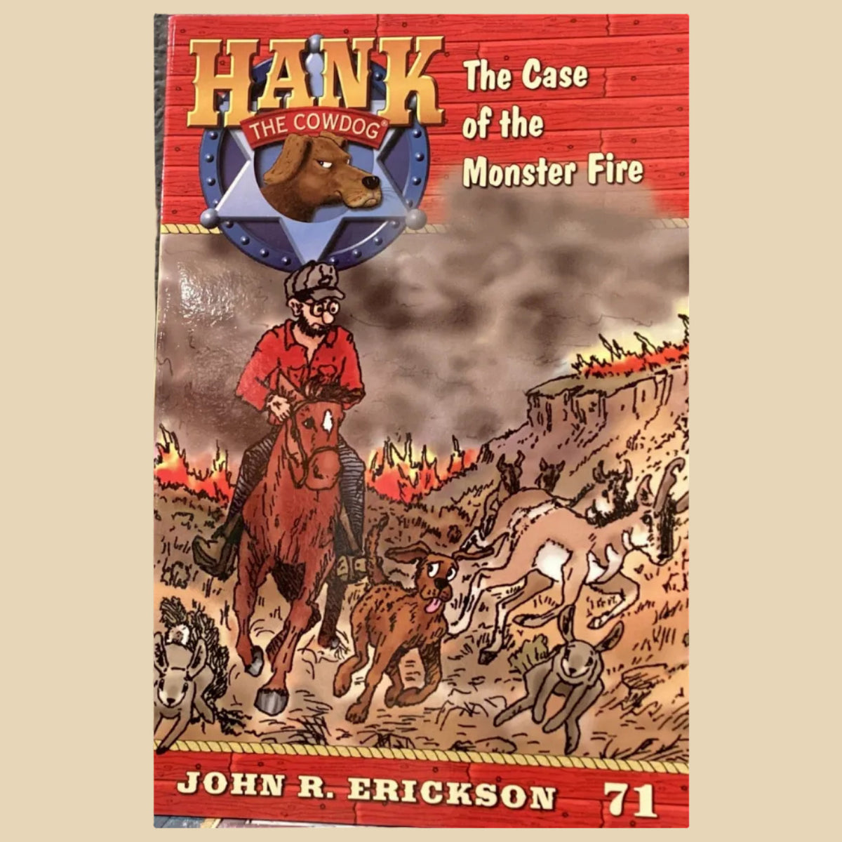 Book titled 'Hank the Cowdog: The Case of the Monster Fire' by John R. Erickson on a gray surface.