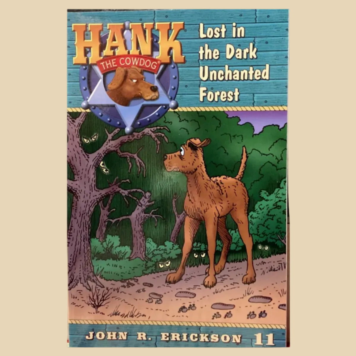 Book titled 'Hank the Cowdog: Lost in the Dark Unchanted Forest' by John R. Erickson on a gray surface.