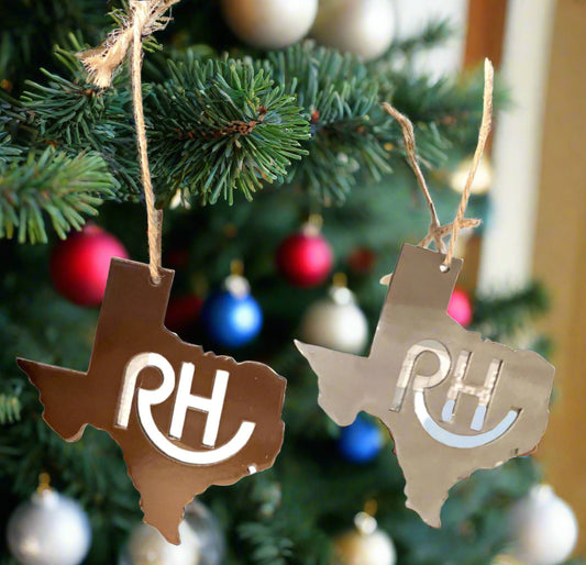 Two cut-out Texas-shaped ornaments with 'RH' initials hanging on a stand against a neutral background.