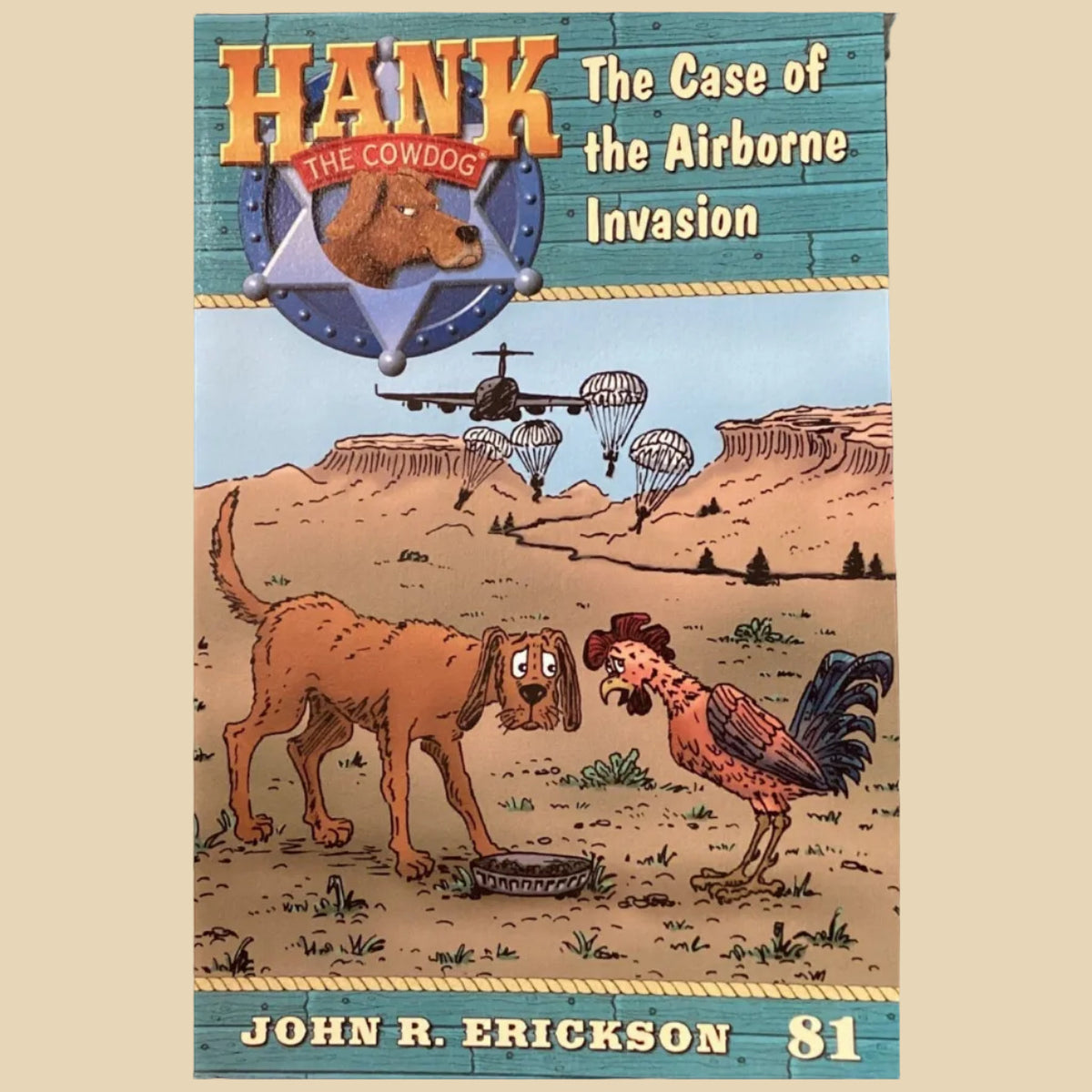 Book titled 'Hank the Cowdog: The Case of the Airborne Invasion' by John R. Erickson on a gray surface.