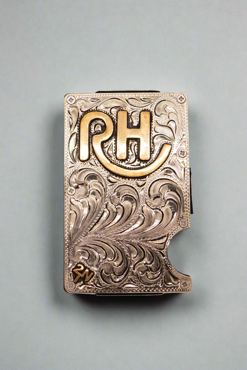 A silver wallet with ornate designs and the initials 'RH' prominently displayed in gold lettering.