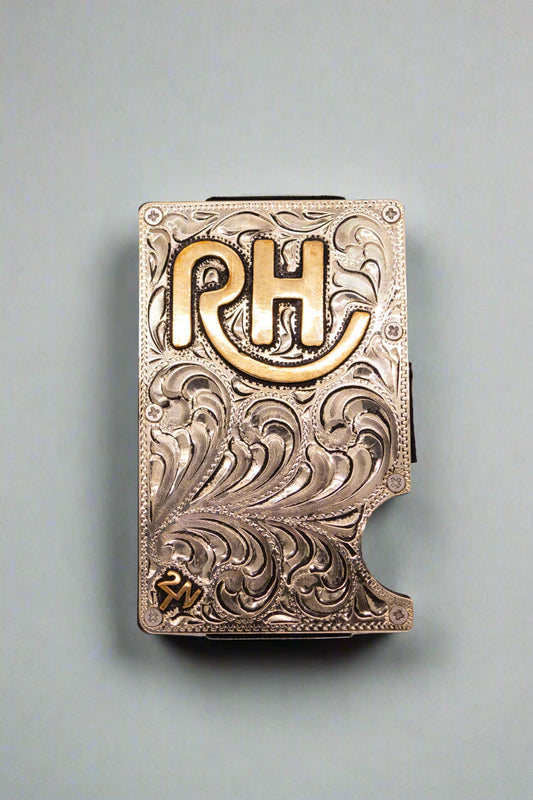 A silver wallet with ornate designs and the initials 'RH' prominently displayed in gold lettering.