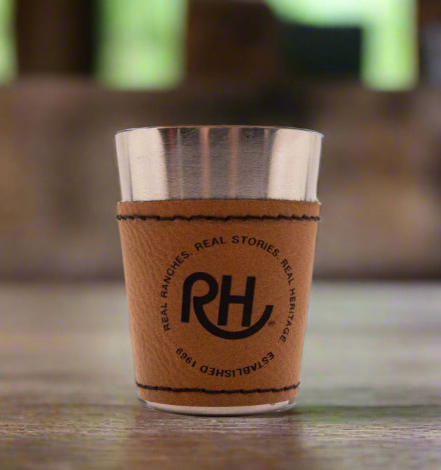 A brown leather wrapped shotglass with metal interior, featuring the RH brand logo.
