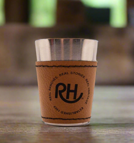 A brown leather wrapped shotglass with metal interior, featuring the RH brand logo.
