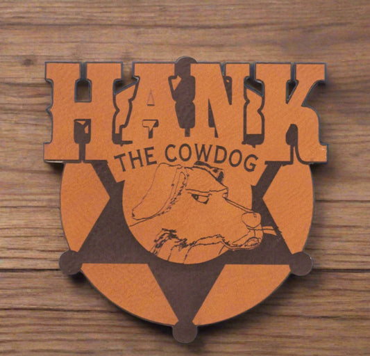 A brown leather magnet with the text 'HANK THE COWDOG' and an illustration of a cow.