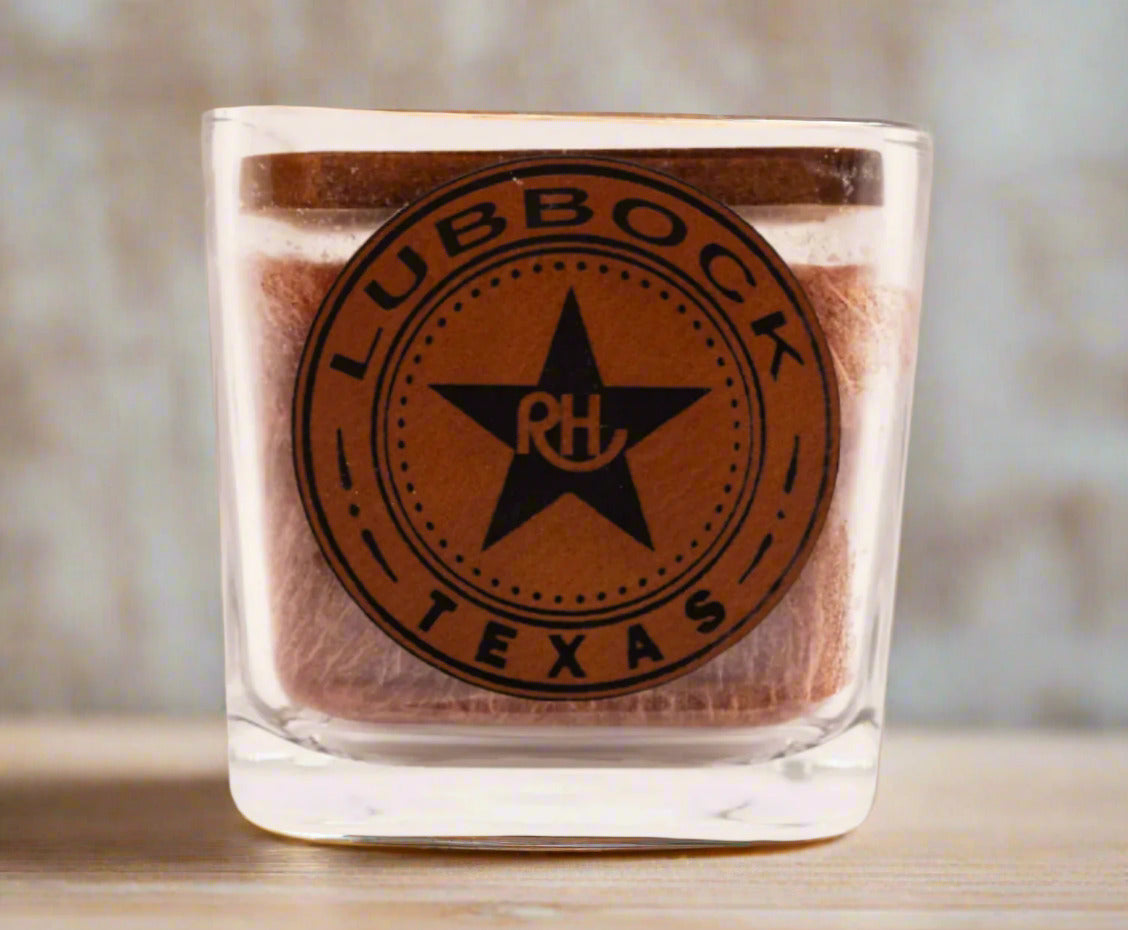 A square-shaped candle with a brown tint and a logo that reads 'RHUBBOCK TEXAS' printed on it.