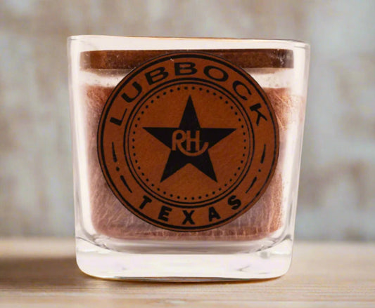 A square-shaped candle with a brown tint and a logo that reads 'RHUBBOCK TEXAS' printed on it.
