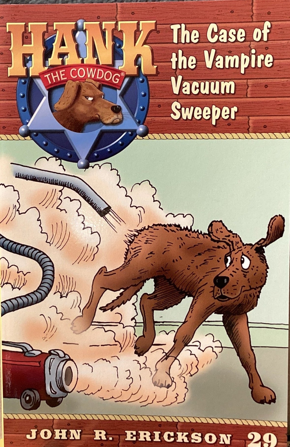Book titled 'Hank the Cowdog: The Case of the Vampire Vacuum Sweeper' by John R. Erickson on a gray surface.