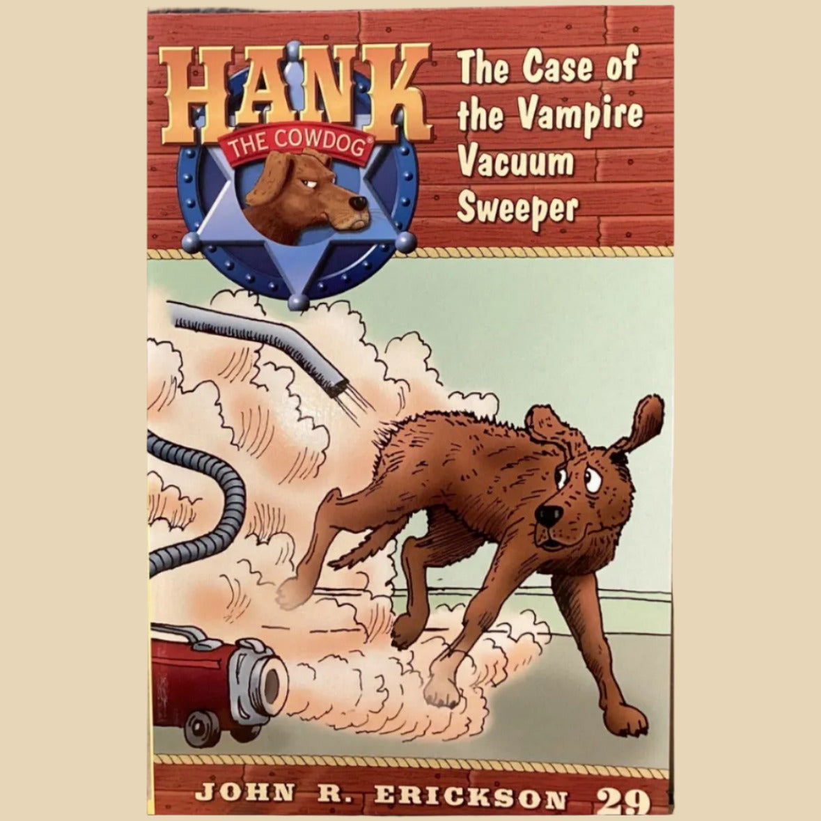 Book titled 'Hank the Cowdog: The Case of the Vampire Vacuum Sweeper' by John R. Erickson on a gray surface.