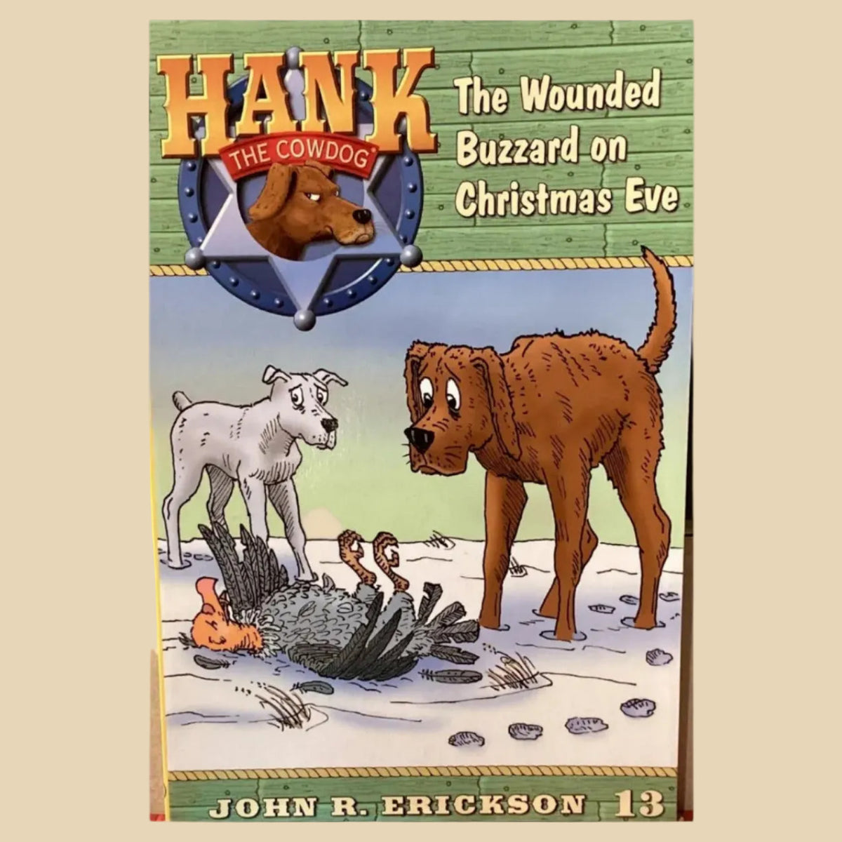 Book titled 'Hank the Cowdog: The Wounded Buzzard on Christmas Eve' by John R. Erickson on a gray surface.
