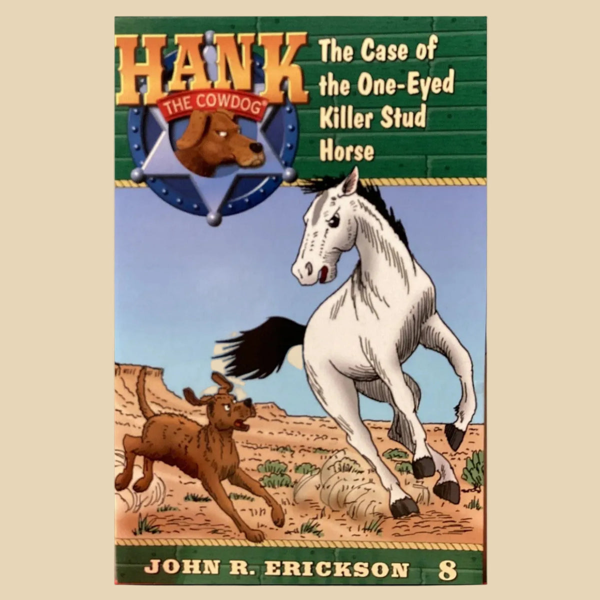 Book cover for 'Hank: The Case of the One-Eyed Killer Stud Horse' by John R. Erickson, showing a white horse and a brown cowdog in a western desert scene, with the title and author text on a black background.