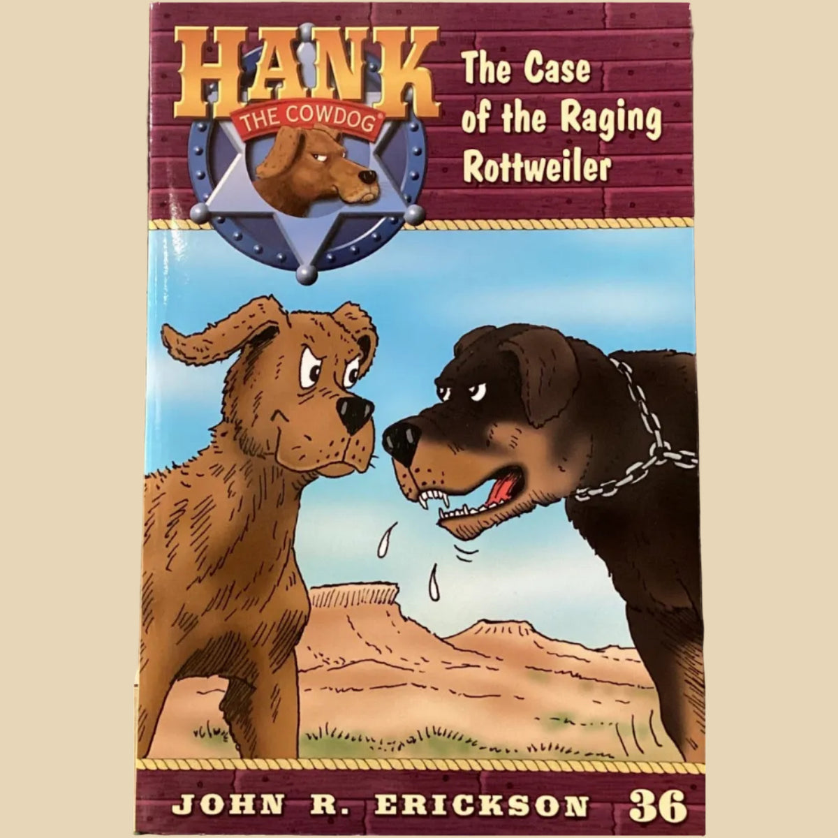 Book titled 'Hank the Cowdog: The Case of the Raging Rottweiler' by John R. Erickson on a surface with a gray wall background.