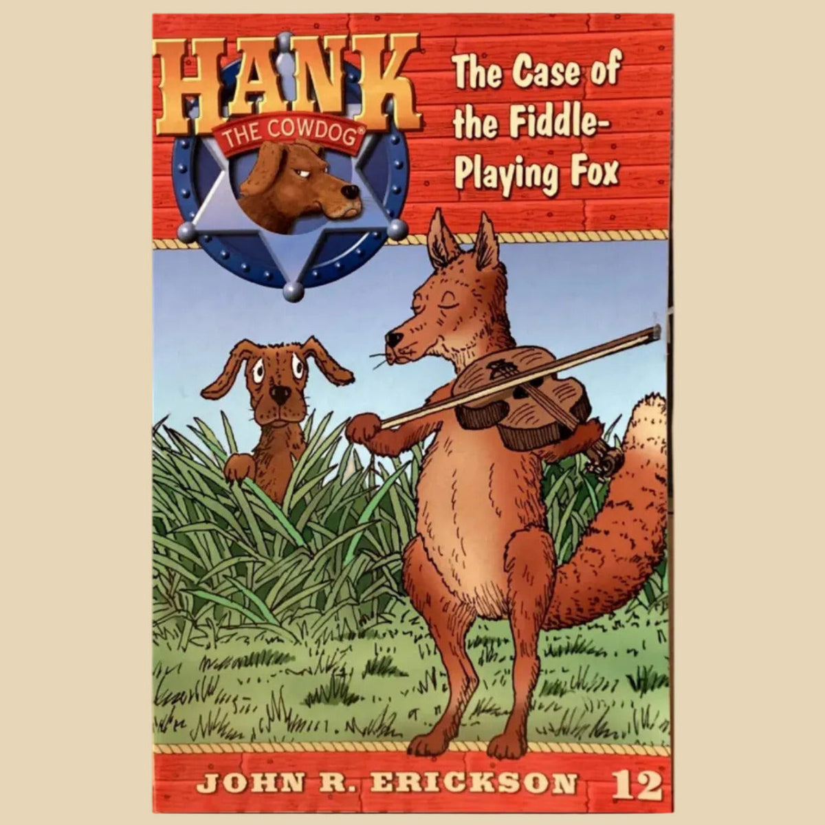 Book titled 'Hank the Cowdog: The Case of the Fiddle-Playing Fox' by John R. Erickson on a gray surface.