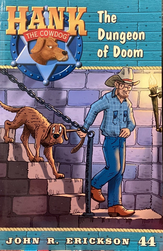 Book titled 'Hank the Cowdog: The Dungeon of Doom' by John R. Erickson on a gray surface.