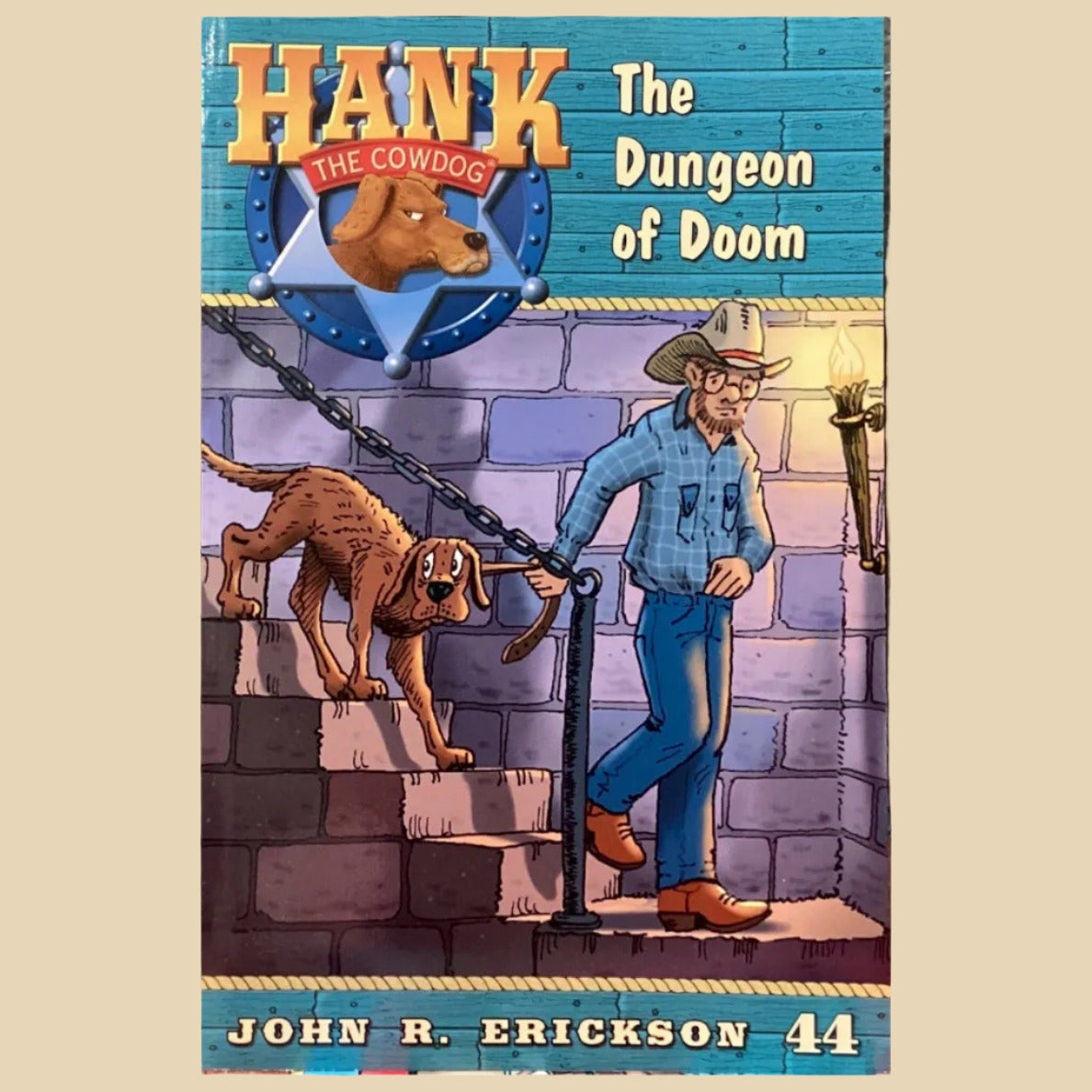 Book titled 'Hank the Cowdog: The Dungeon of Doom' by John R. Erickson on a gray surface.