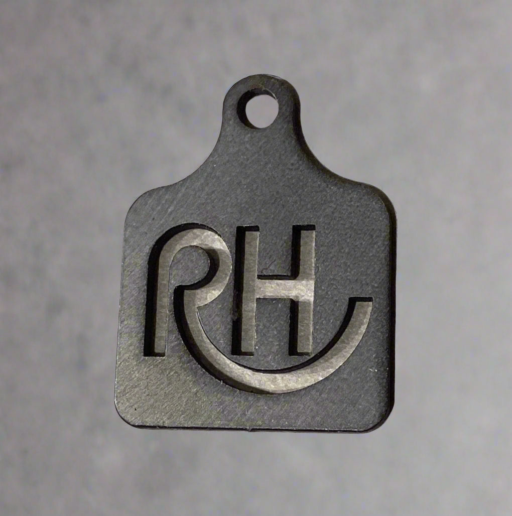 Black metal tag with 'RH' initials on a beige background