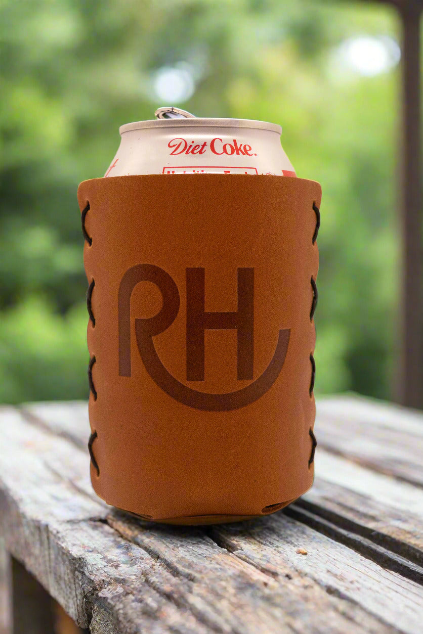 A brown leather koozie with the initials 'RH' embossed on the front, holding a can of Diet Coke.
