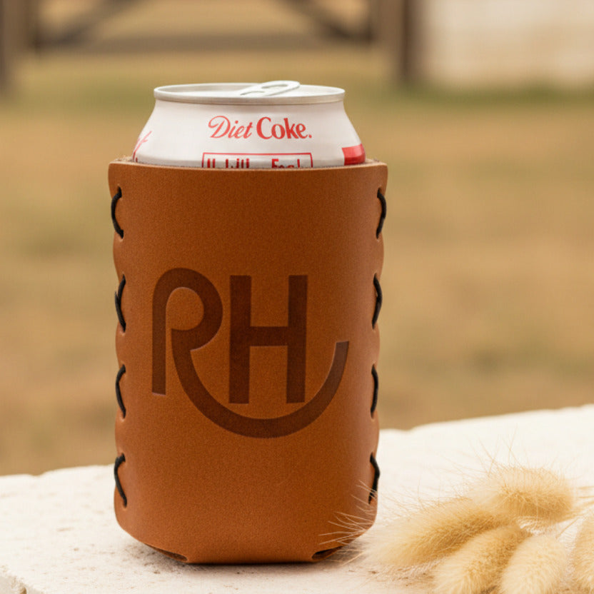 A brown leather koozie with the initials 'RH' embossed on the front, holding a can of Diet Coke.