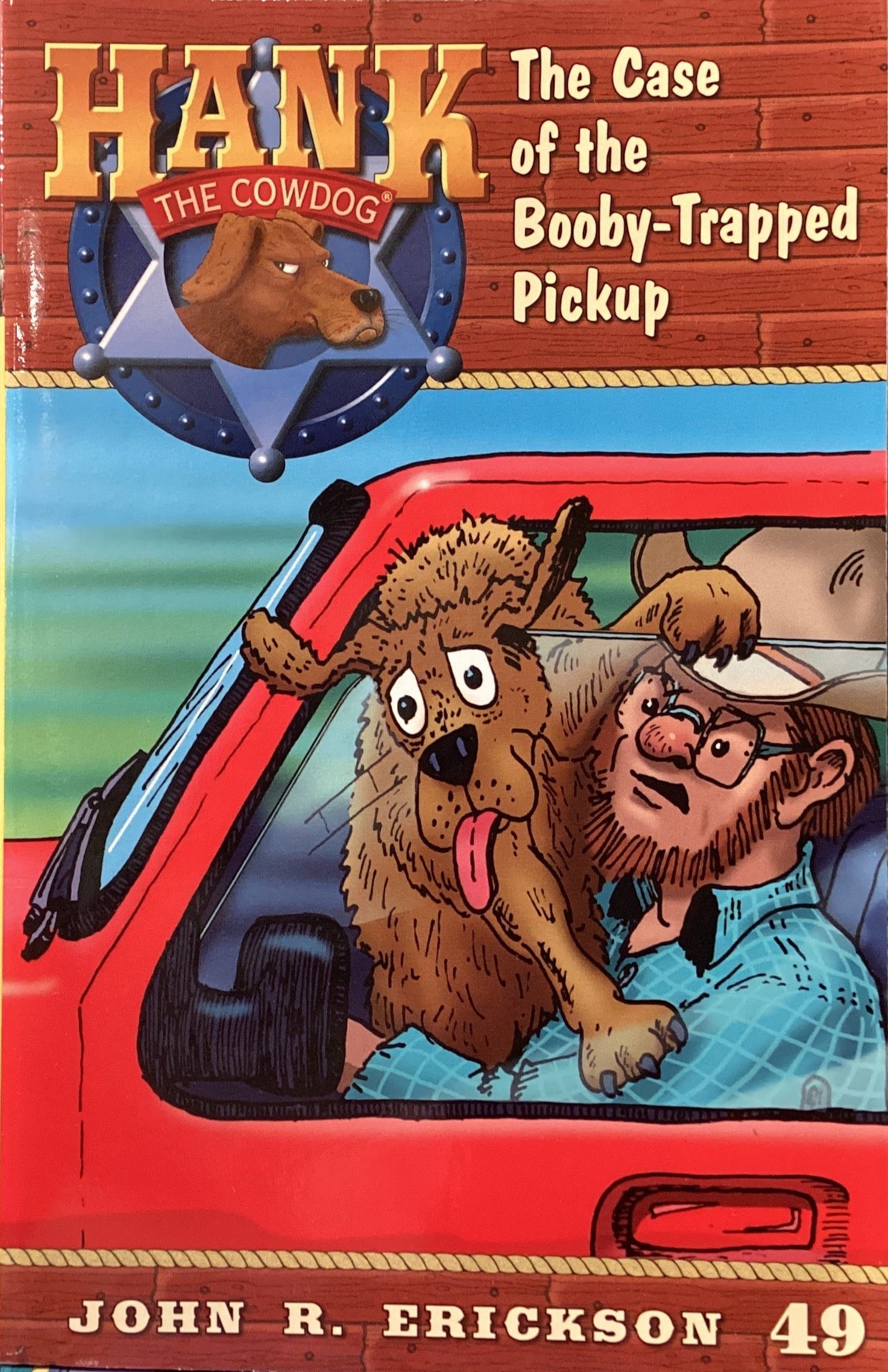 Book titled 'Hank the Cowdog: The Case of the Bobby-Trapped Pickup' by John R. Erickson on a gray surface.