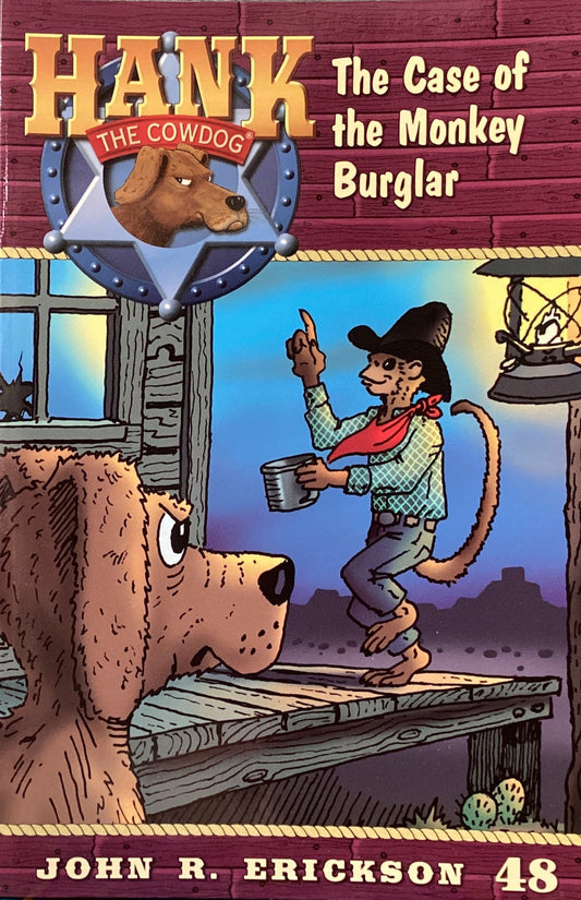 Book titled 'Hank the Cowdog: The Case of the Monkey Burglar' by John R. Erickson on a gray wall.