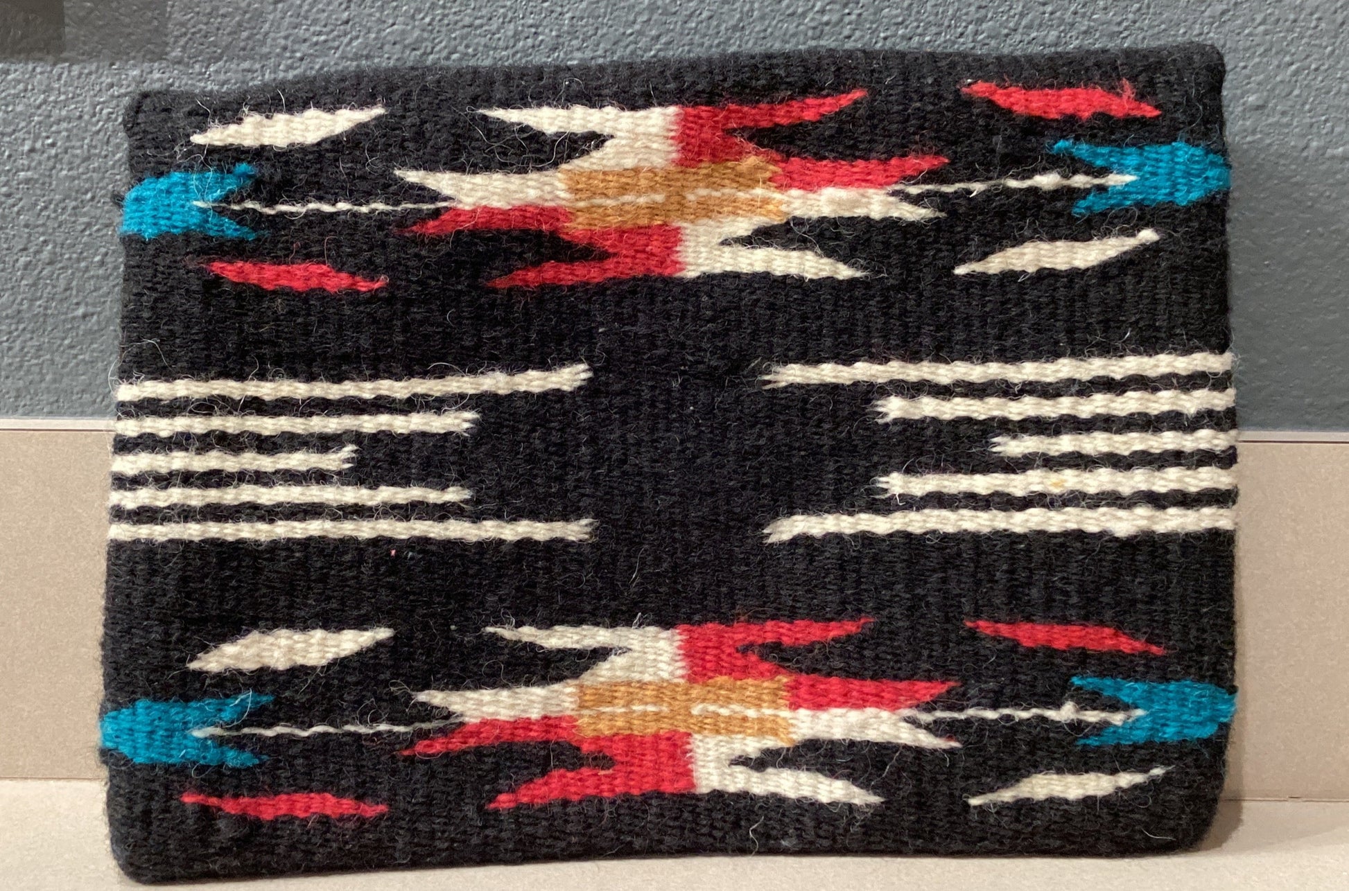 Woven pouch with geometric pattern on a gray surface