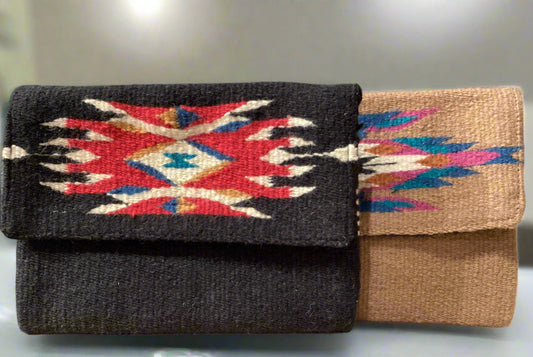 Two handbags with geometric patterns, one black and one beige, against a gray wall.