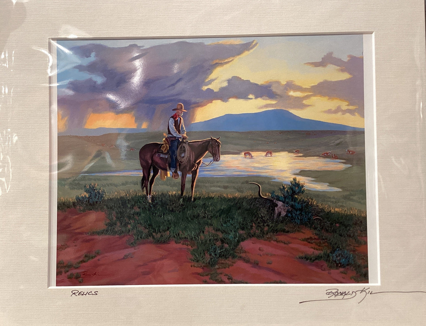 Framed artwork of a cowboy on horseback with a scenic landscape.