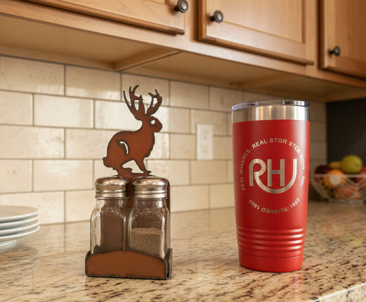 Decorative salt and pepper shakers with a metal deer stand next to a red canister on a wooden surface.