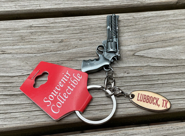 Keychain with red tag and gun charm on a wooden table