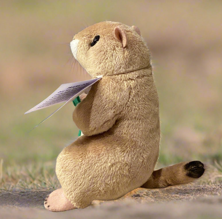 Plush prairie dog toy holding a purple flag on a neutral background
