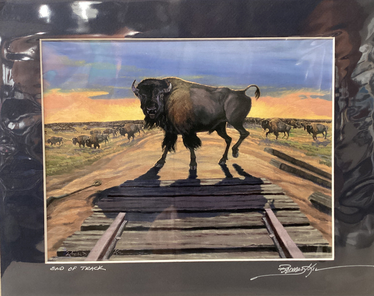 Framed artwork of a bison on railroad tracks with a scenic background