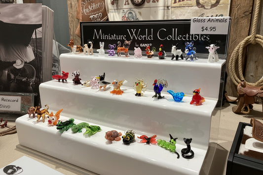 Collection of miniature glass animals on display with a price tag in the background.