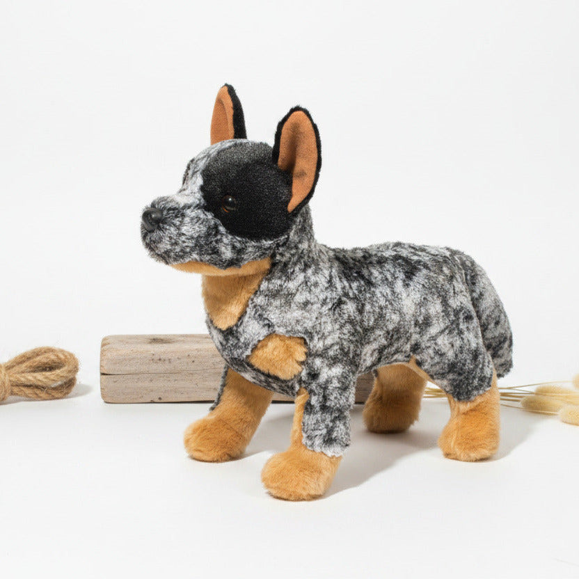 A plush toy dog with a black and gray mottled coat, tan muzzle, chest, and paws, and black ears with tan inner linings, shown on a plain white background.